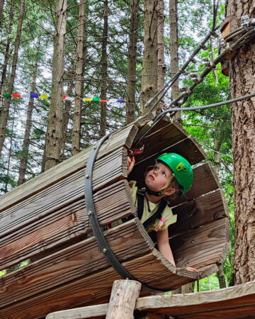 Une fillette traverse un tunnel dans le cadre d'un parcours d'accrobranche.